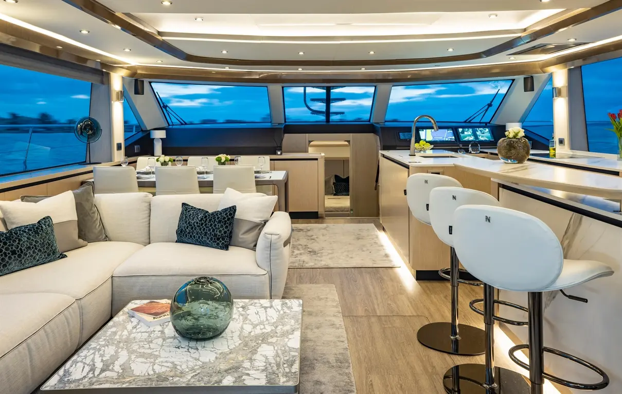 Luxurious yacht interior featuring a spacious lounge with a marble coffee table, modern kitchen, and panoramic windows.